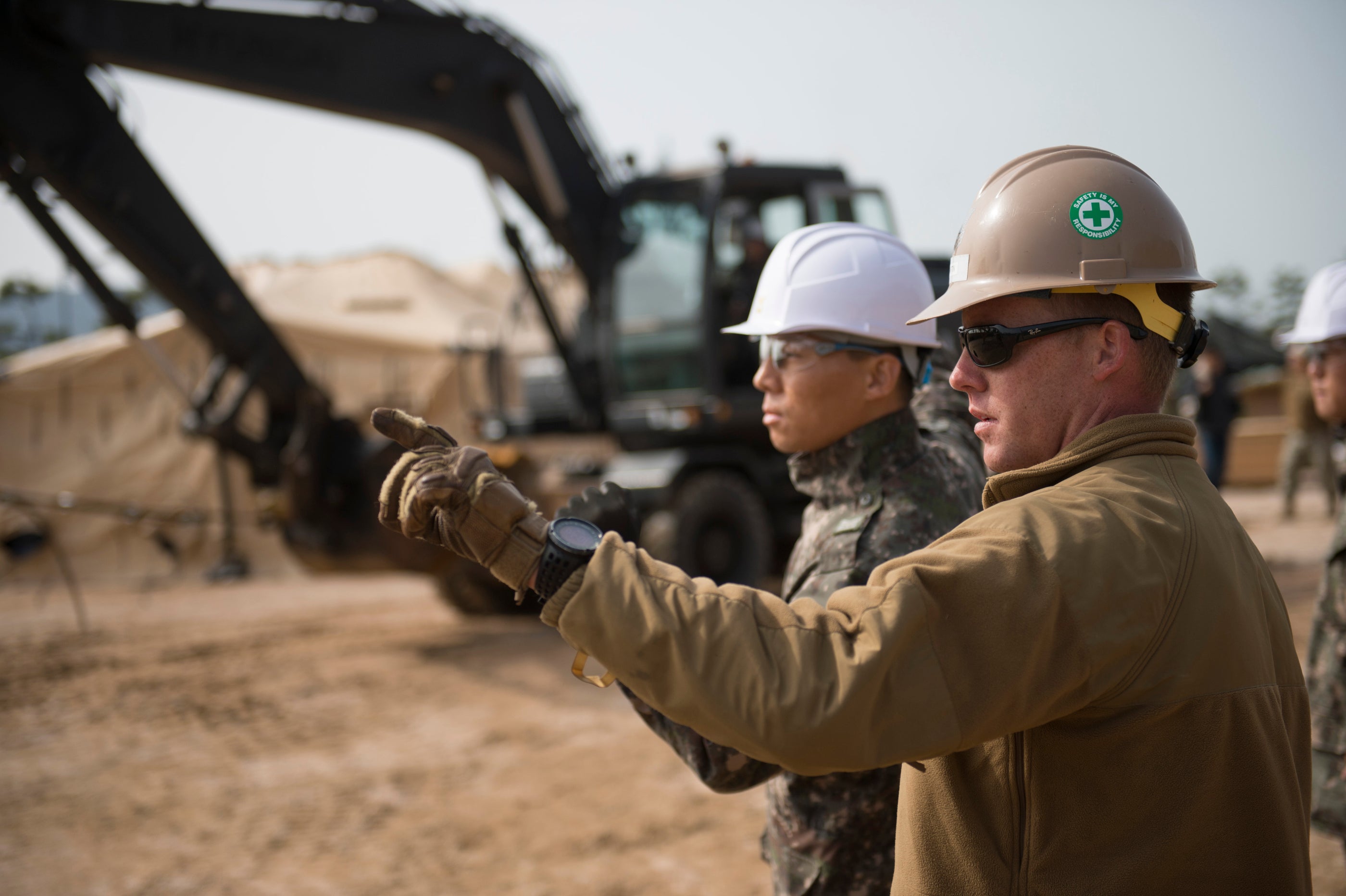 This image shows two construction workers discussing the process, with the construction machinery in the back.