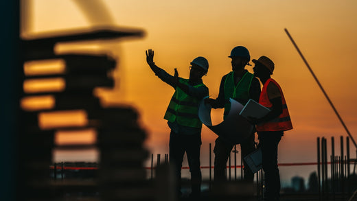 Construction workers are discussing the construction during the sunset.